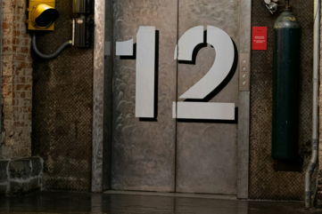 A yellow traffic light sitting next to a metal door